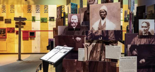 A museum exhibit showcasing people made up of modular photos. A timeline runs in the background.