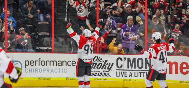 Image is of two Cincinnati Cyclones players on the ice with fans in the background cheering.