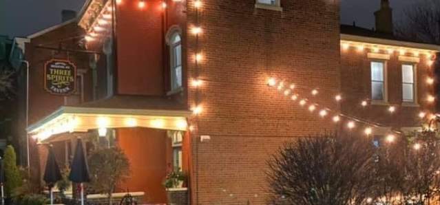 A red brick building at night with glowing lights around the exterior and over a courtyard.
