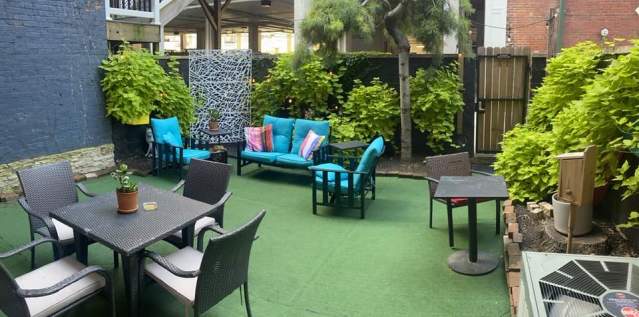 A private patio with several seating options. Green plants grow lush along the wall.