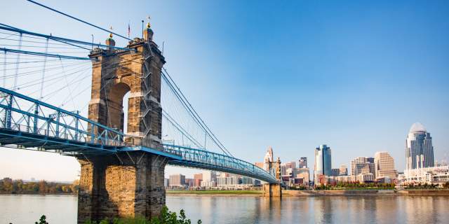The Roebling Suspension bridge leading to downtown Cincinnati's skyline under a sunny blue sky