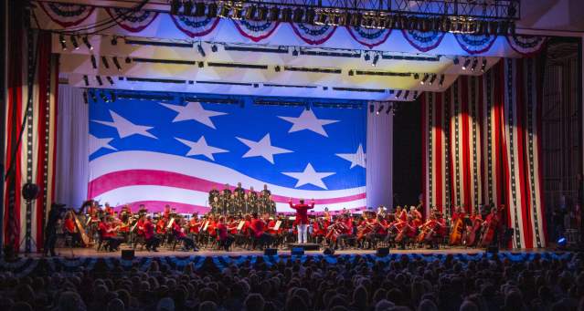 The Cincinnati Symphony Orchestra performs onstage with American flag decor as a backdrop