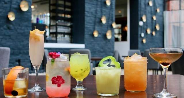 A row of various cocktails, colored pink, yellow, amber and green at Coppin's Restaurant in Covington, Ky.