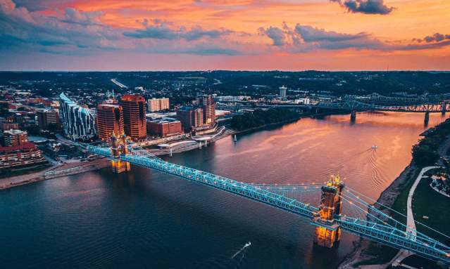 Sunset in the background over the Ohio river with the John A. Roebling Suspension bridge spanning from NKY to Cincy