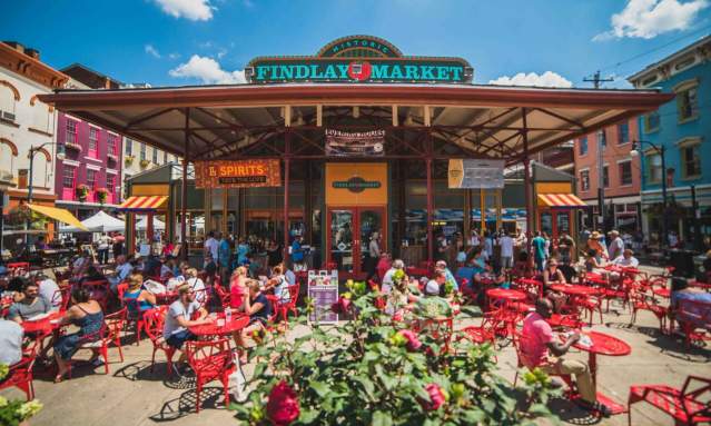 Exterior of Findlay Market showing the sign. Many bistro tables fill the patio for people to sit and eat.