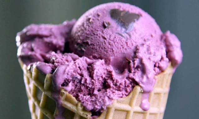 A waffle cone with vibrant purple ice cream studded with dark chocolate chips.