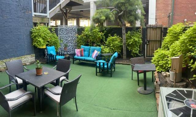 A private patio with several seating options. Green plants grow lush along the wall.