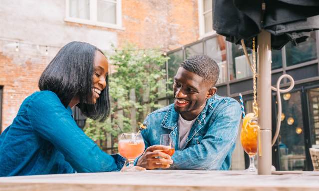 Young Black couple smiling at a table on the patio of Coppin's Restaurant at the Hotel Covington