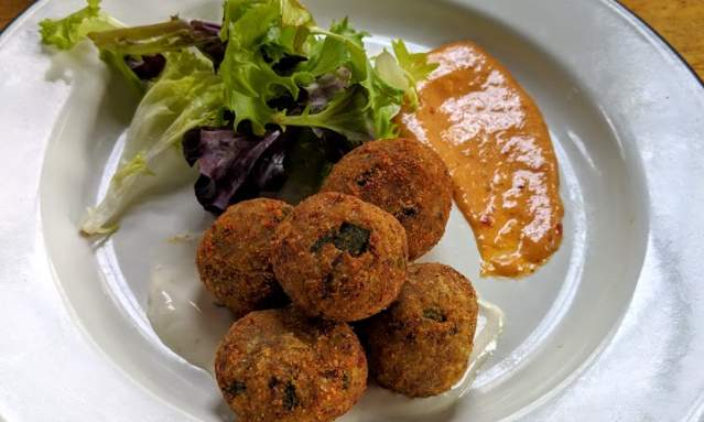 goetta hush puppies from libbys southern comfort in covington ky with green garnish and sauce on the side of a white plate