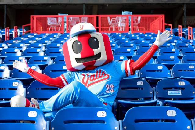 An anthropomorphic version of the famous red and white striped Florence, KY watertower, dressed in a blue and red Florence Y'alls uniform. It sits in the stadium seats arms stretched wide.
