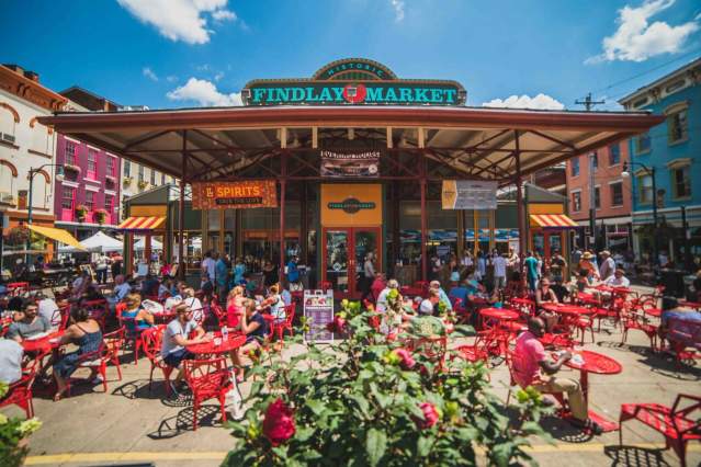 Exterior of Findlay Market showing the sign. Many bistro tables fill the patio for people to sit and eat.