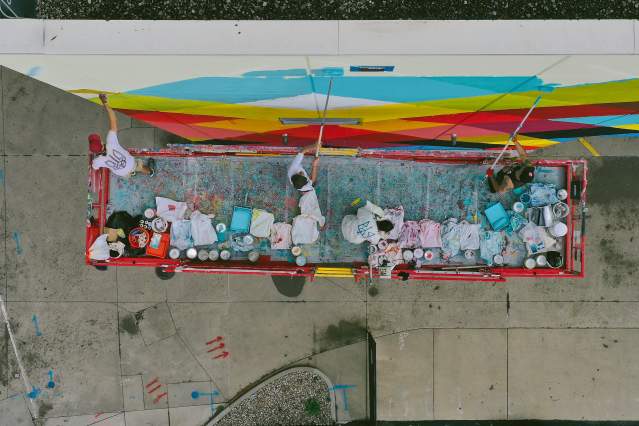 An aerial view of a crew painting a mural on the side of a building