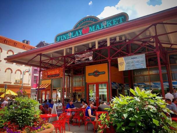 The entrance of Findlay Market during the day with couples sitting at tables surrounded by flowers.