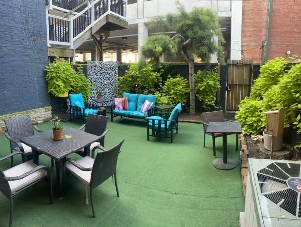A private patio with several seating options. Green plants grow lush along the wall.