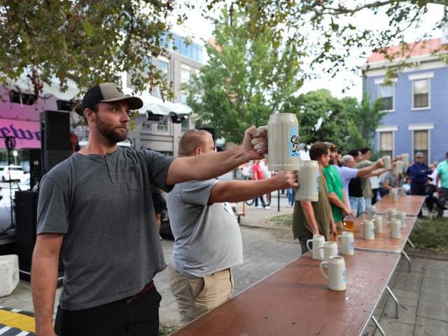 A group of men hold steins straight out in front of them during a stein-holding competition at Oktoberfest