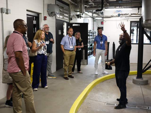 A group of people listen to a tour guide at New Riff Distilling.
