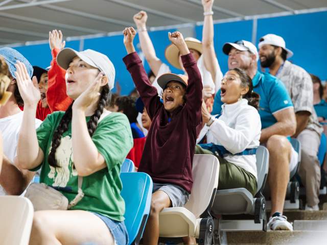 Rows of seated fans at the Cincinnati Open cheer during a tennis match