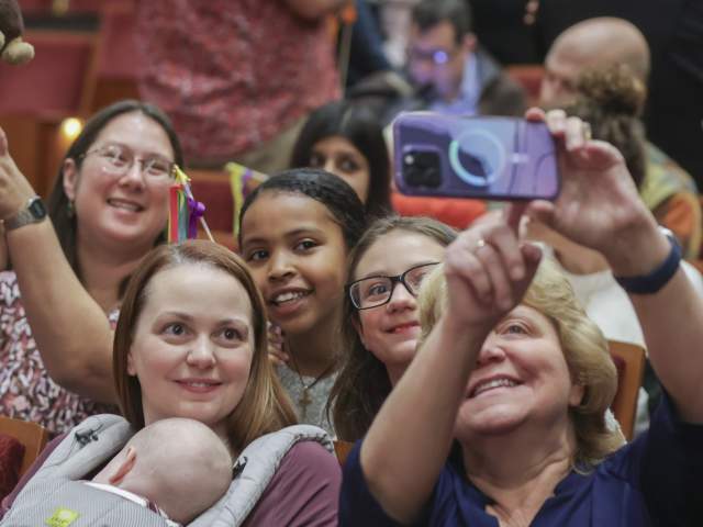 A group of people in the audience at the Cincinnati Symphony Orchestra take a photo.