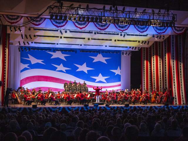 The Cincinnati Symphony Orchestra performs onstage with American flag decor as a backdrop