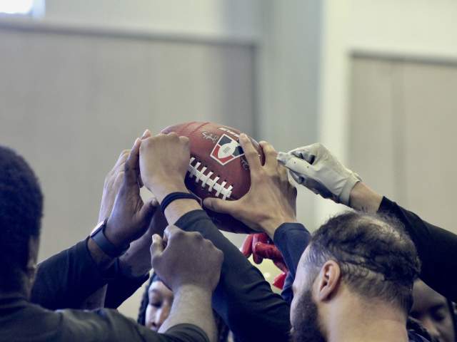 Team members touch a football.