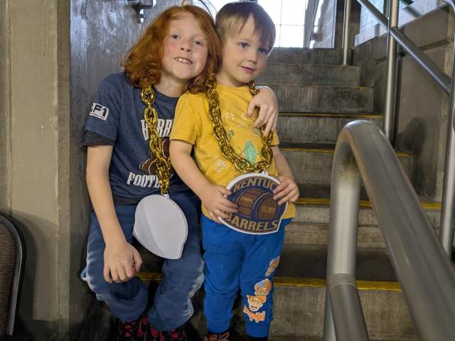 Two kids are wearing large necklaces with Kentucky Barrel logos.