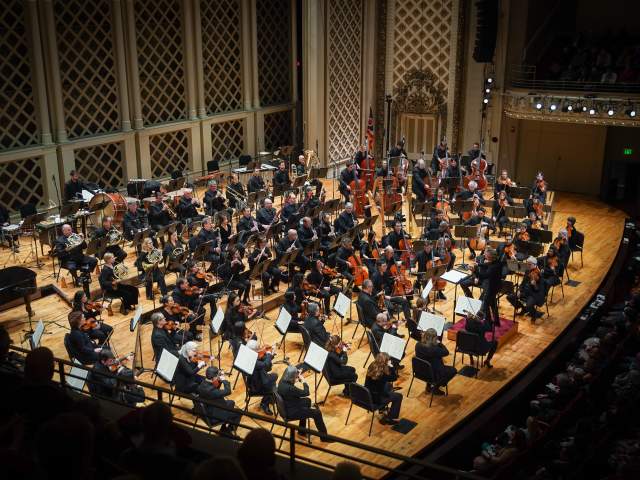 A group of musicians are assembled onstage at the Cincinnati Symphony Orchestra.