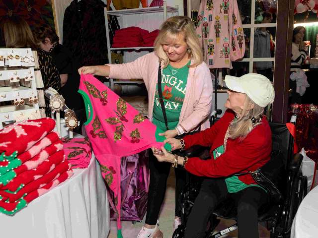 Two women peruse festive holiday sweaters at the Greater Cincinnati Holiday Market