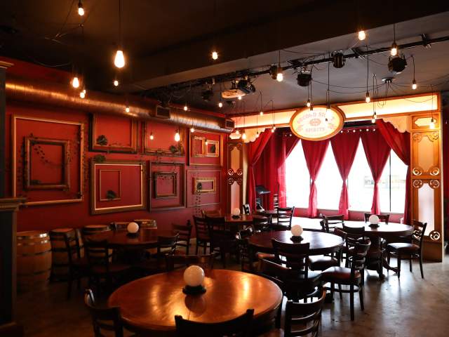 Event space at Second Sight Spirits with small stage and round tables with crystal ball lights
