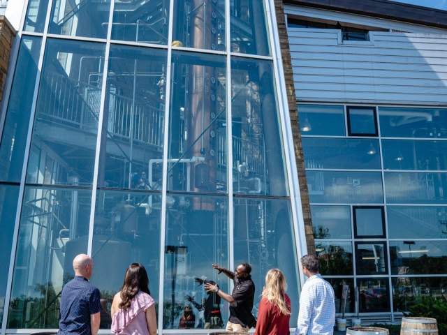 A man showing a group of people the column still at New Riff Distilling