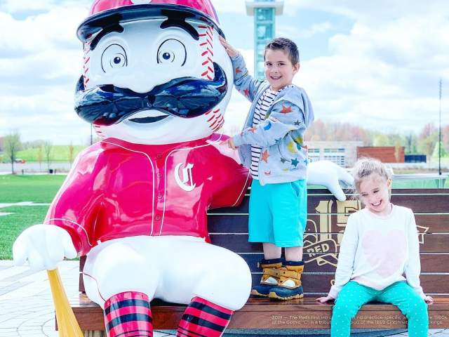photo of the cincinnati reds mascot with two kids sitting on bench for 150th anniversary of major league baseball celebration in cincinnati oh
