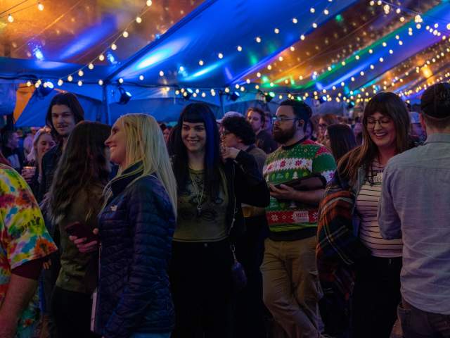 A group of people, watching the stage, smiling, and having a good time.