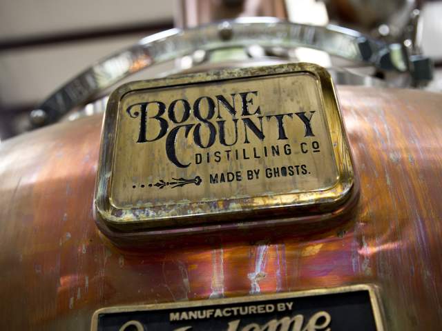 A closeup photo of a copper still. The tags on the still say Boone County Distilling Co. Made by Ghosts and Manufactured by Vendome Copper and Brass Works Inc. Louisville, Kentucky
