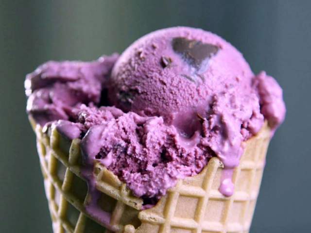 A waffle cone with vibrant purple ice cream studded with dark chocolate chips.