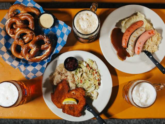 A variety of German dishes laid out including schnitzel, sausages, and soft pretzels.