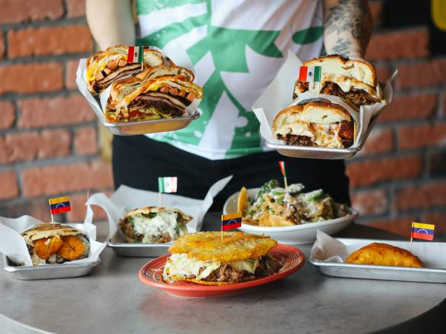 A person holds two dishes over a table with several others.
