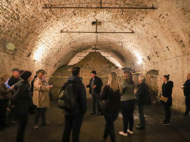 A group of people gather to listen to a tour guide in one of Cincinnati's underground lagering tunnels.