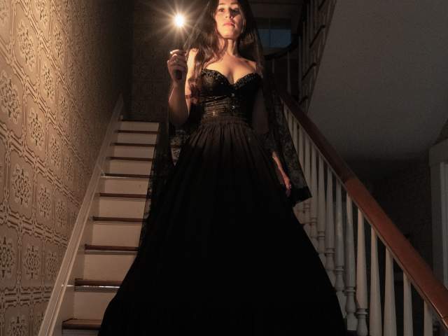 Paranormal historian, Violet Shindler, descending a staircase at the Heritage Village Museum during a paranormal investigation tour.