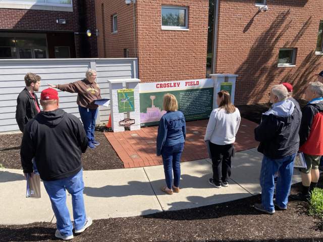 A tour group stands in front of a sign that says Crosley Field.