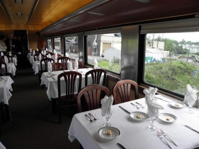 A restored dining car on the Cincinnati Dinner Train. Tables are formally set with white linens, cut glasses, and silverware.