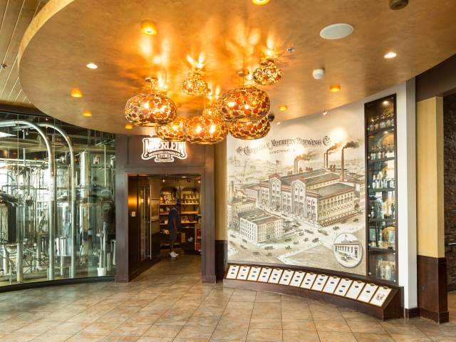 The front entrance at Moerlein Lager house with globe lighting and an illustration of the brewery on the wall.