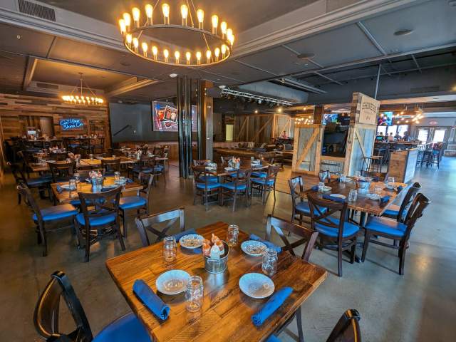 Multiple wooden tables set at Shiners on the Levee. The stage is visible in the background.