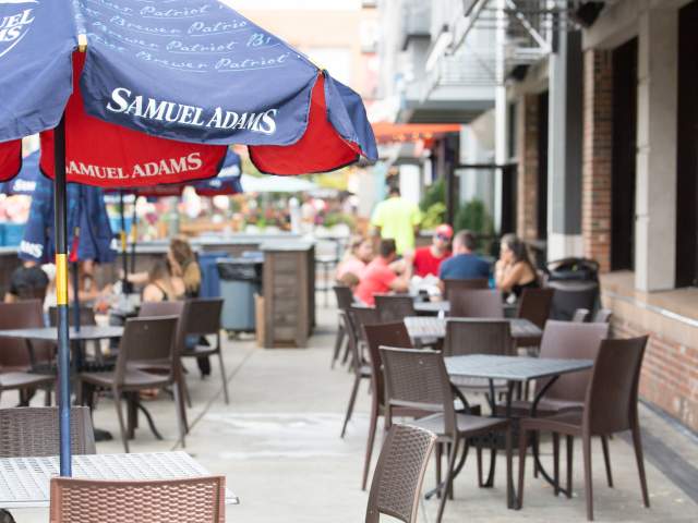 An outdoor patio at The Banks. Brown tables are set up and groups of people are in the background.