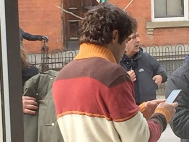 Image is of the back and side view of Zac Efron dressed as Ted Bundy in Mainstrasse.
