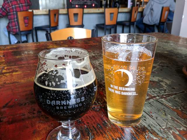 Two glasses of beer, one light one dark, on a wood table at Darkness Brewing in Bellevue Ky.
