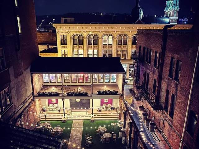 Looking down on an illuminated patio with brick walls and the turrets of Mother of God church in the background