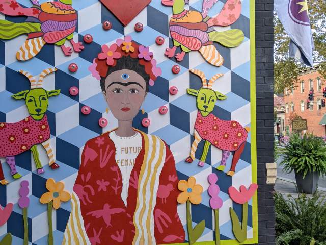 A mural designed to look like a multi-colored quilt with a portrait of Frida Kahlo in the center
