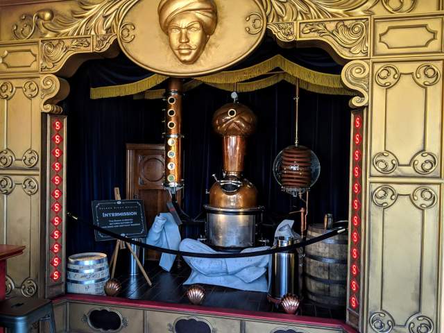 A still shaped like a fortune teller, under a gold theater awning at Second Sight Spirits