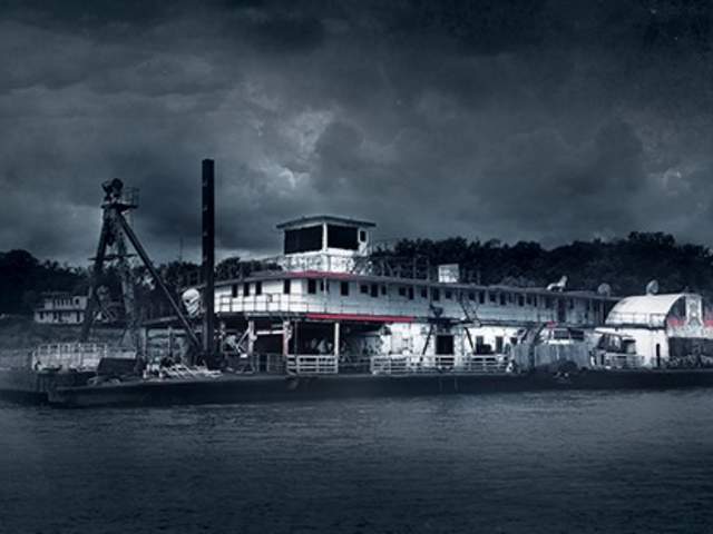 The USS Nightmare, a ship, is on the water, moodily lit, with fog and a clouded sky.