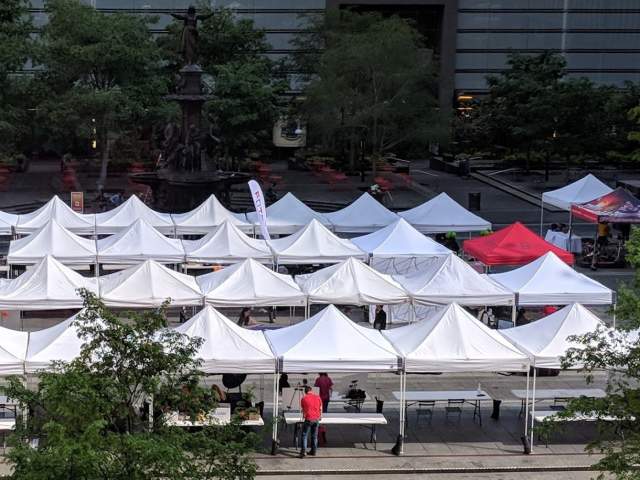 Rows of white tents on Fountain Square in Cincinnati with one red tent that reads "The B-Line" in blue lettering