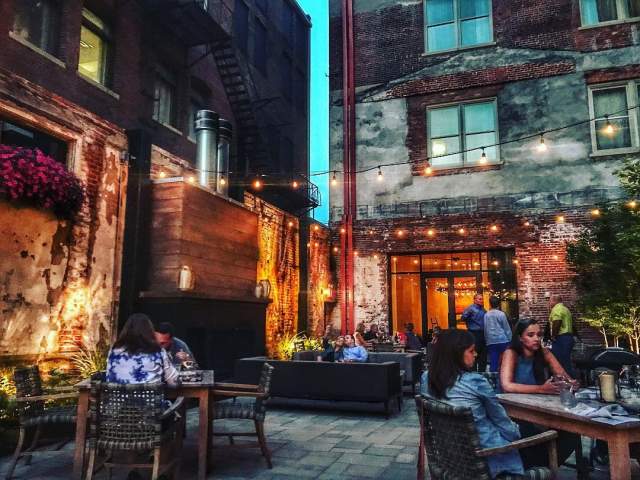 patio area of Coppin's at Hotel Covington restaurant and bar. mood lighting overhead and people gathered dining and drinking at tables on a patio